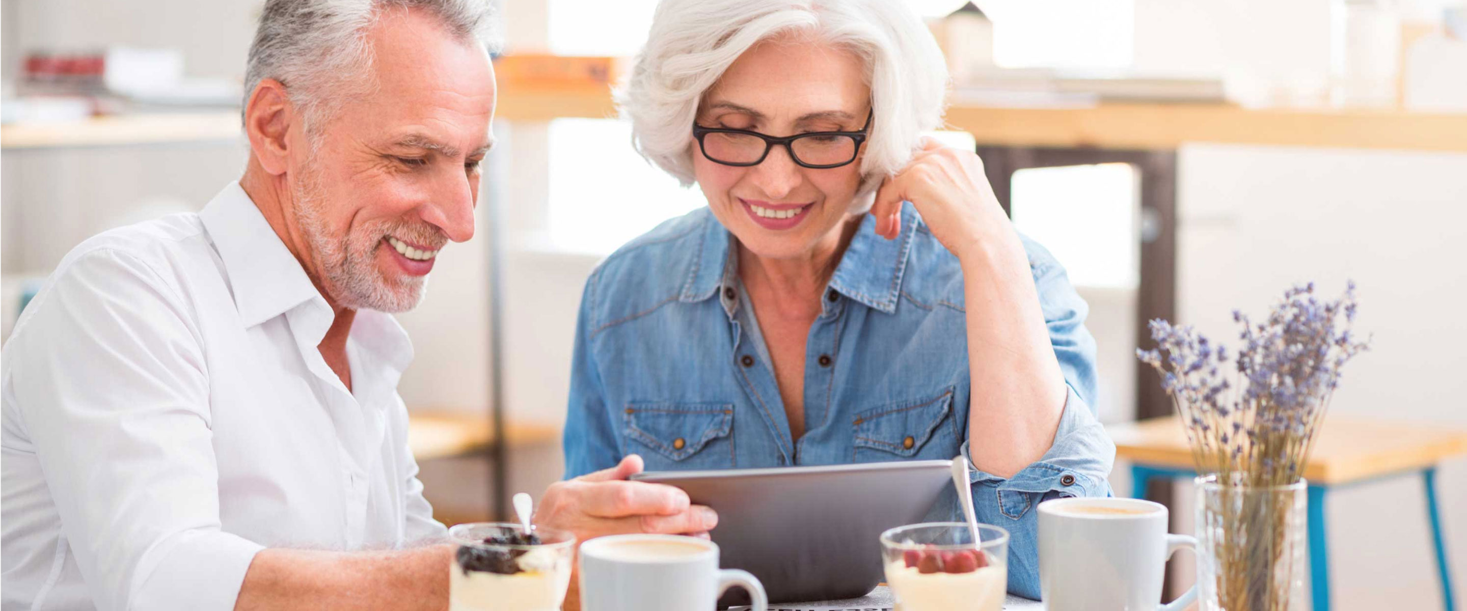 Man and woman looking at a laptop while sitting on the couch, learning about EnergyWiseMN Partnering in Smart Energy Solutions – Own Your Power Program